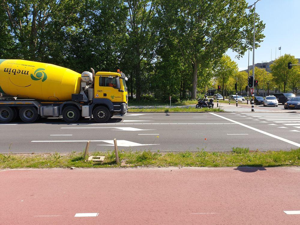 De grote gele betonwagen en de auto's vallen door hun grote en kleuren meer op dan de motorrijder